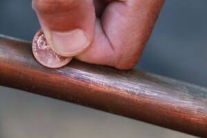 Copper pipe being scratched with a copper penny.