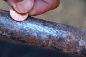 Lead pipe being scratched with a copper penny.